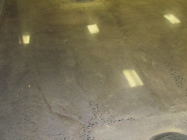 Dim indoor floor with scattered bright reflections and a small speckled patch near the bottom right.