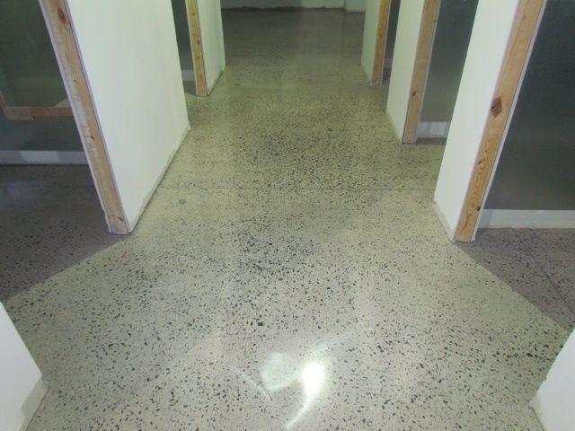 Empty hallway with speckled tile floor and doorways on both sides