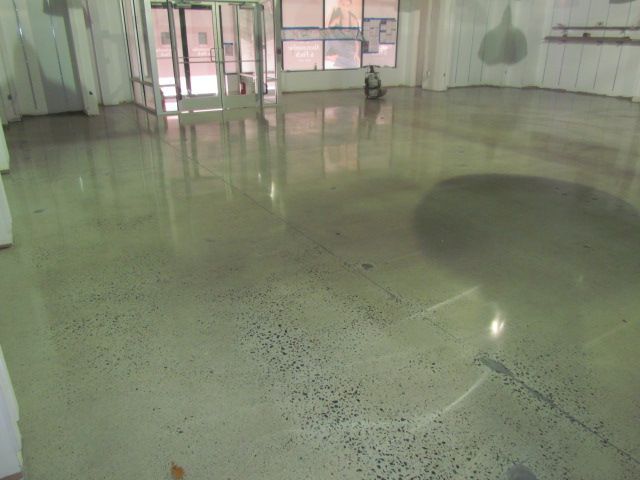 Empty indoor room with a glossy green floor and windows at the back.