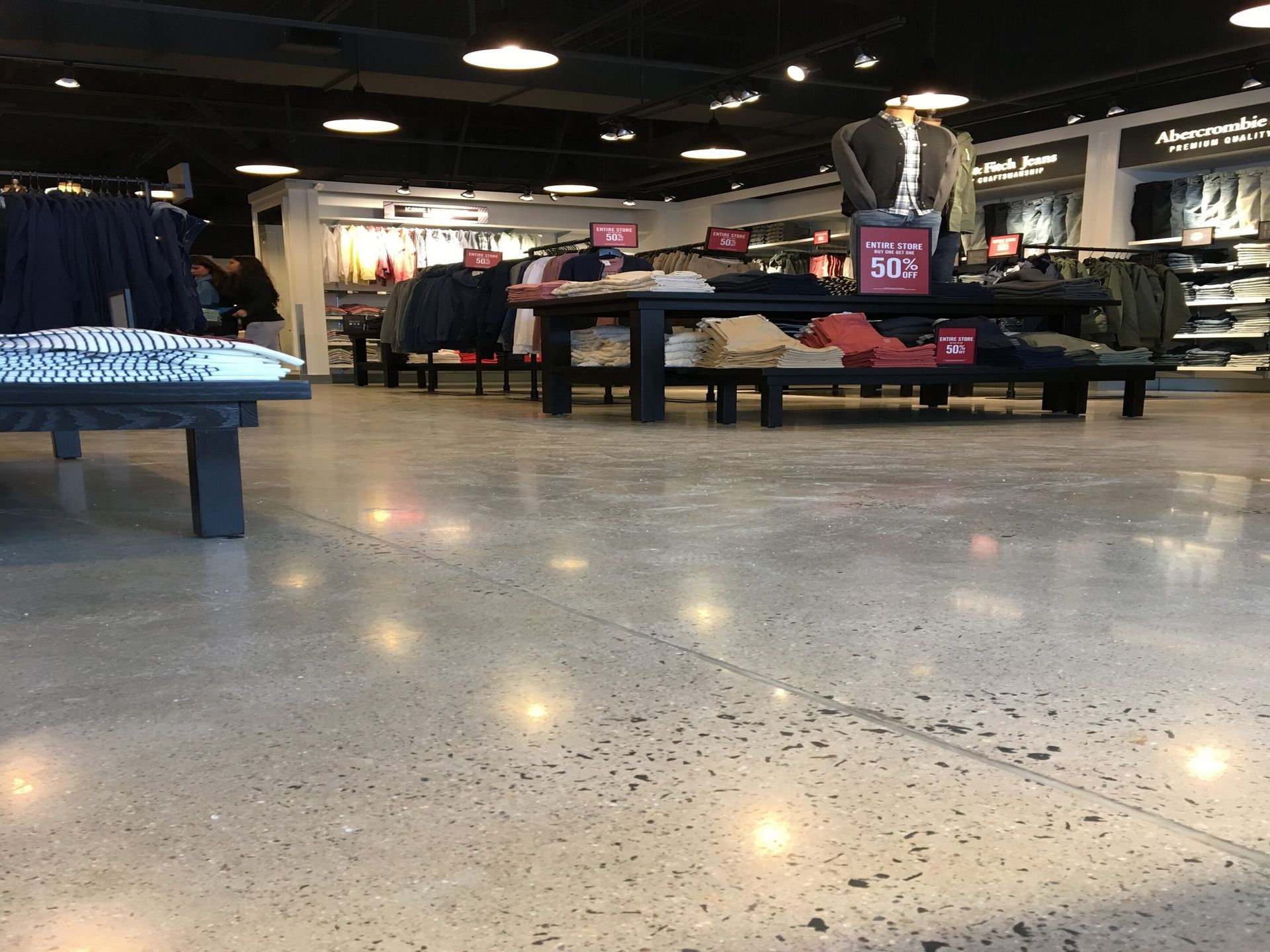 Shoe store interior with bright lights, tables of shoes, and speckled polished floor