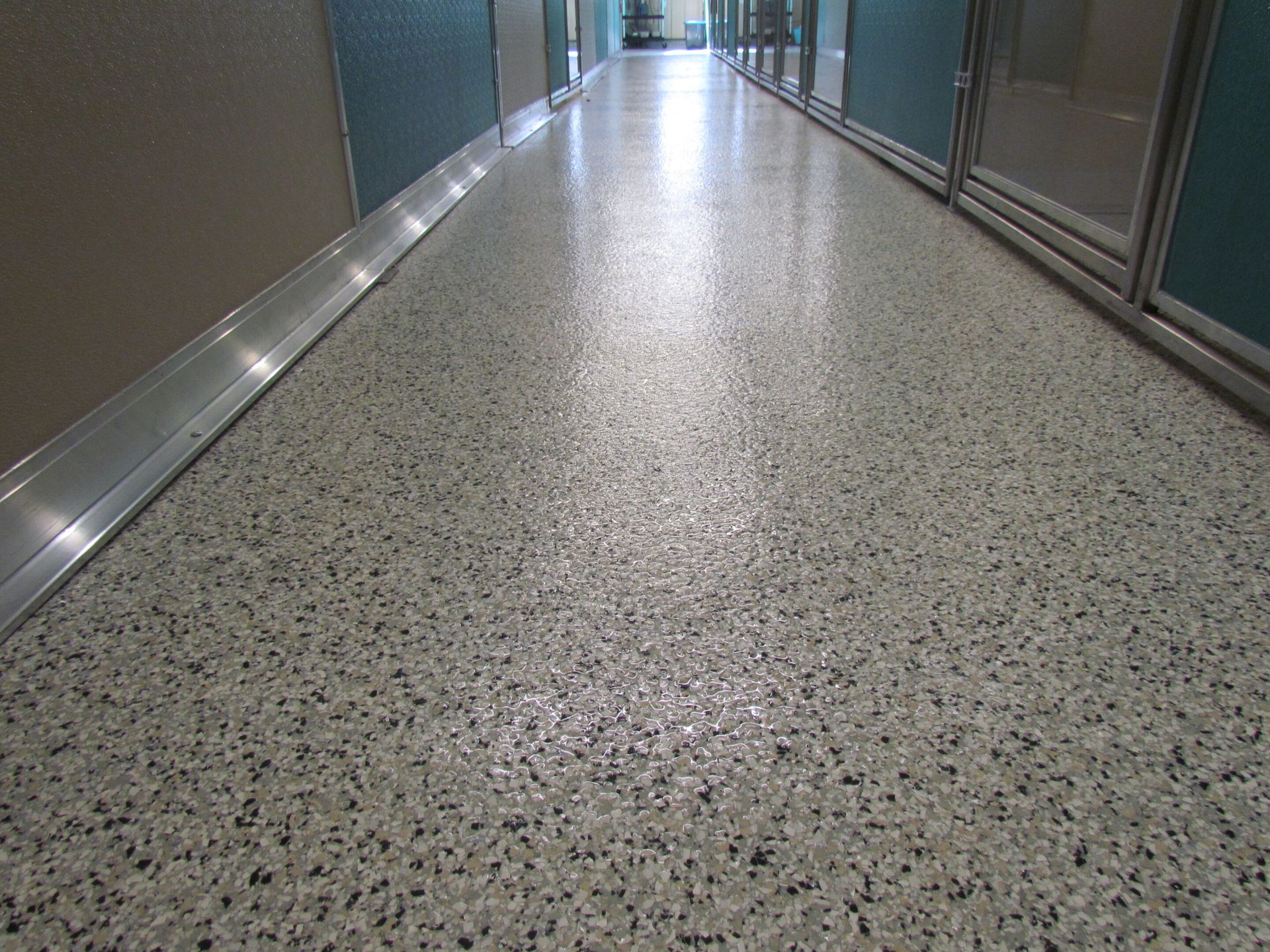 Empty speckled hallway floor between glass walls