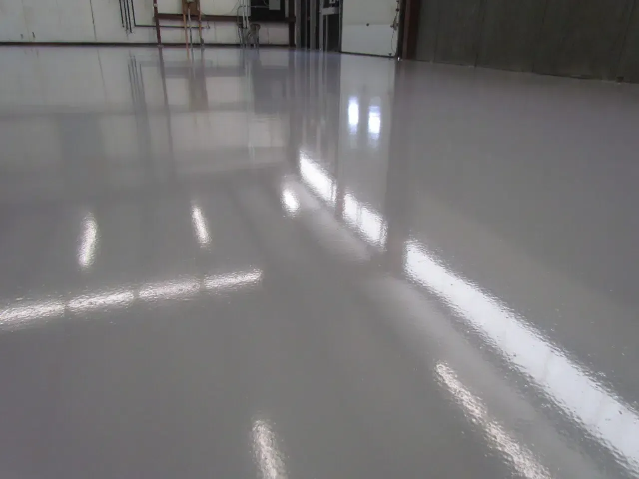 Glossy empty indoor floor reflecting overhead lights in a warehouse-like space