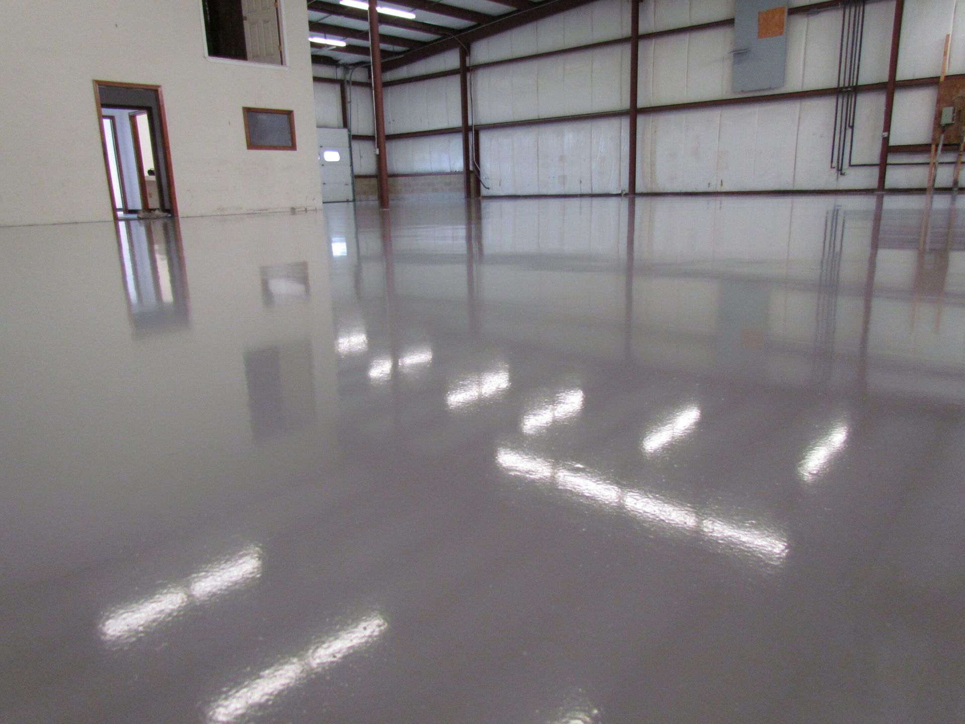 Empty polished warehouse interior with white walls and bright floor reflections