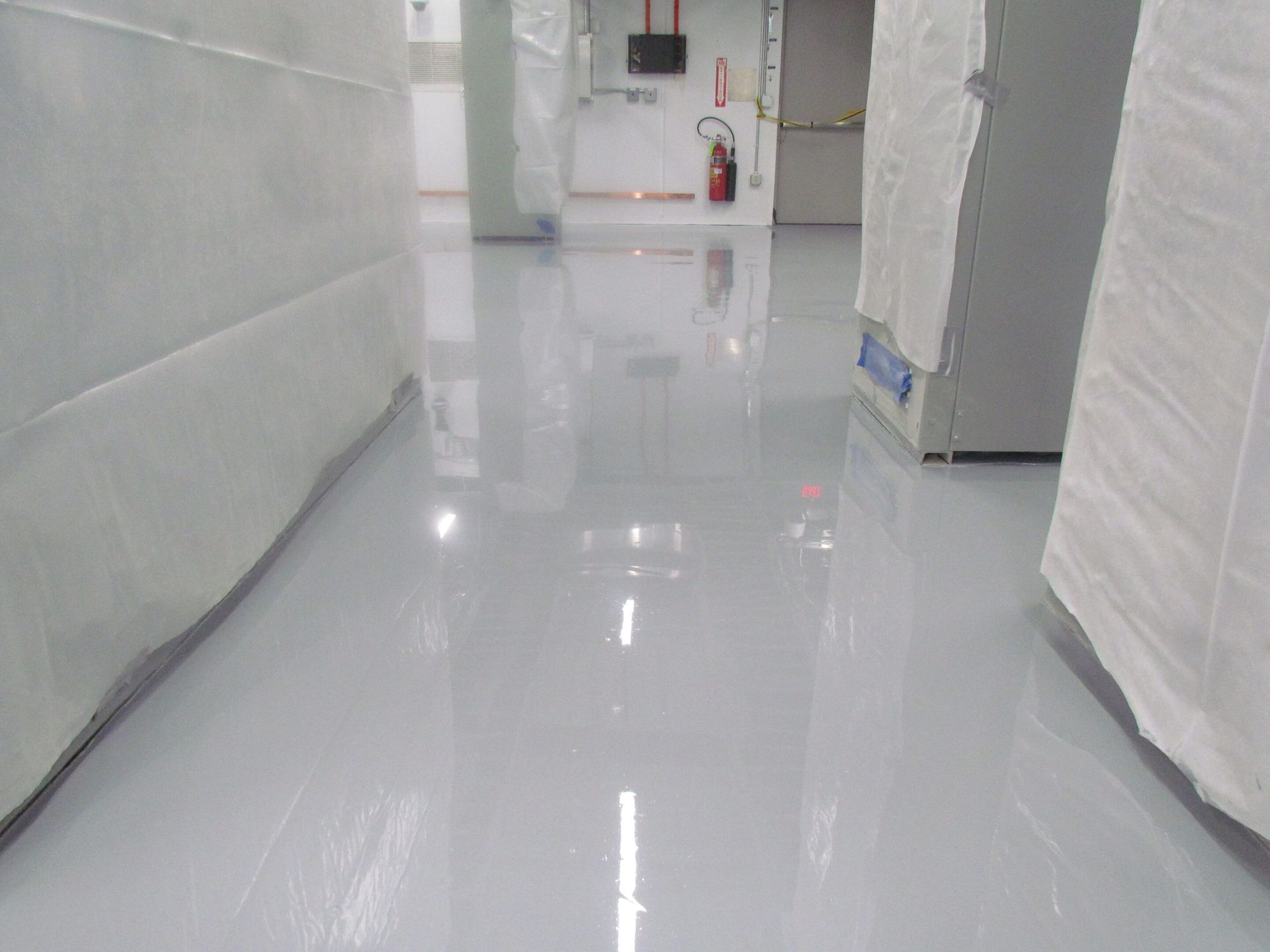 Empty white hallway with a glossy floor and a fire extinguisher at the far end