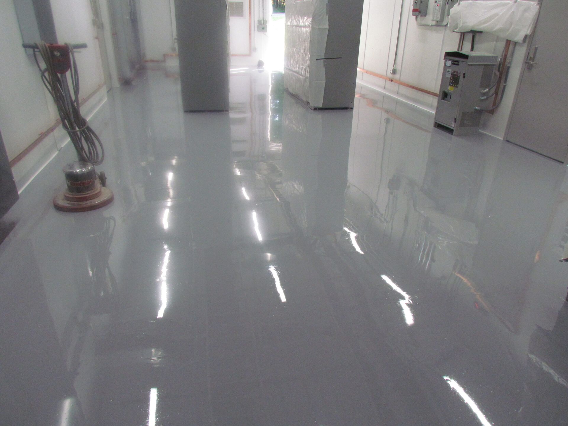 Shiny hospital corridor with white walls, reflective floor, and cleaning equipment on the left