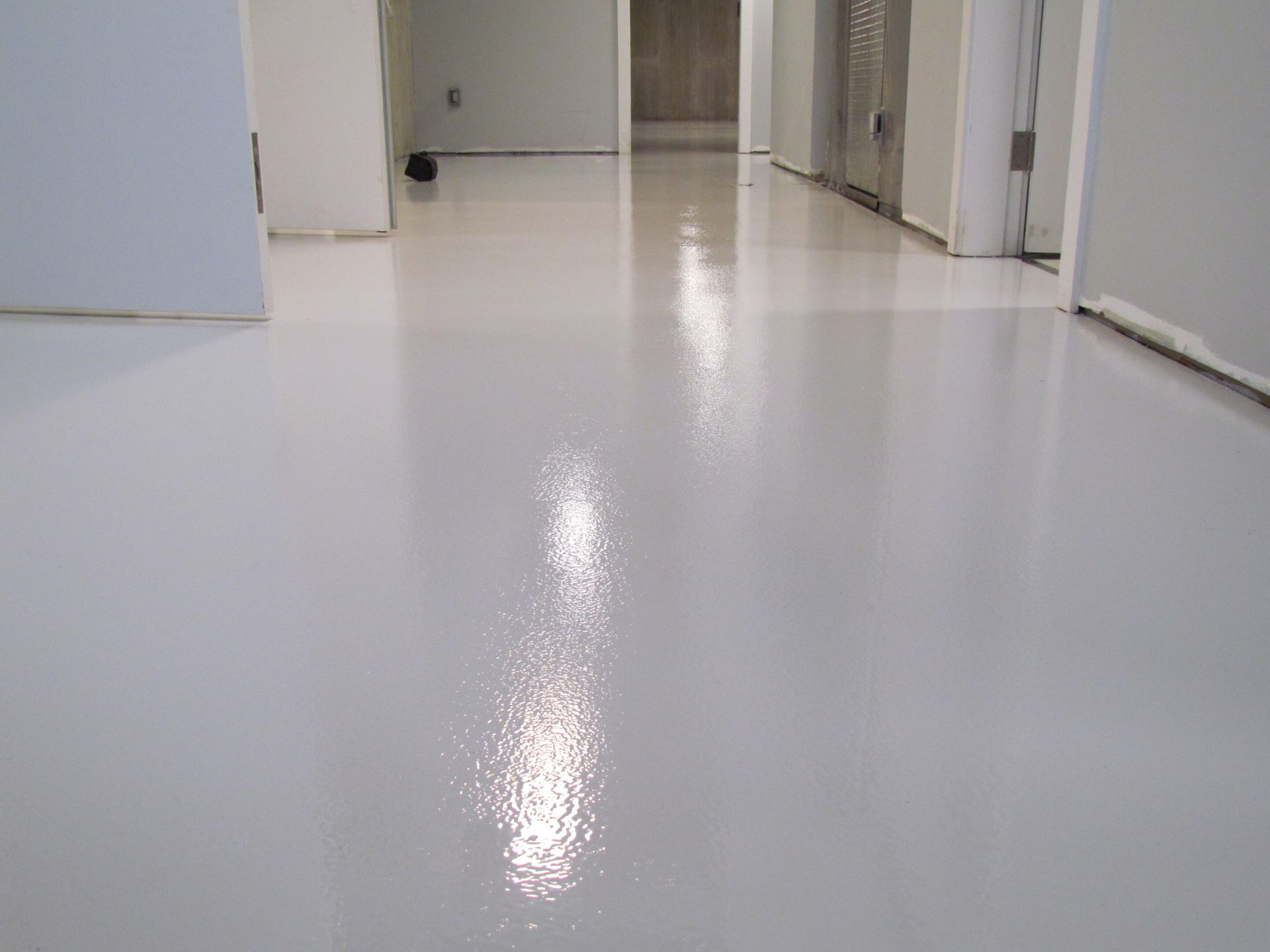 Empty white hallway with glossy floor and doorways on both sides