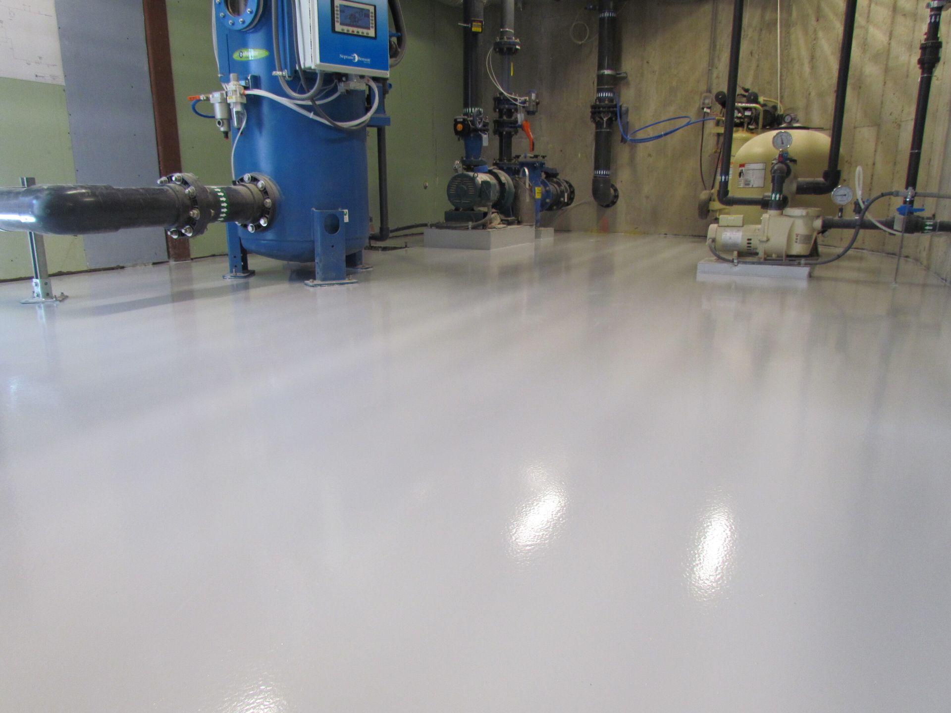 Industrial room with blue machinery and shiny polished floor reflecting overhead lights