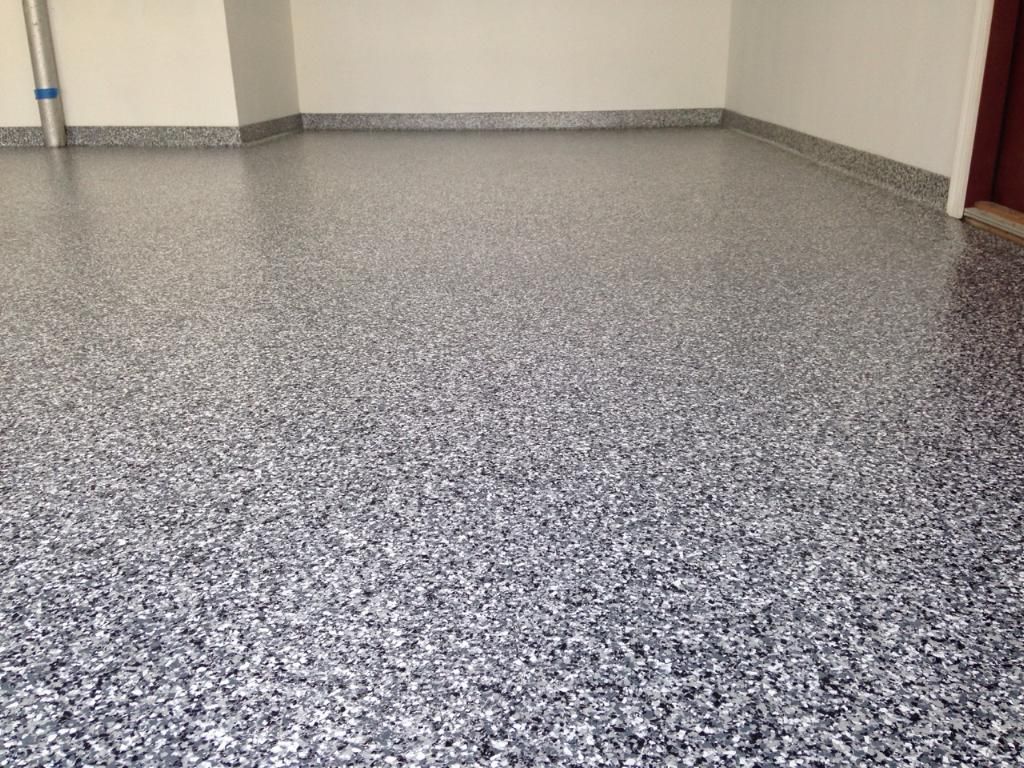 Empty speckled gray floor in a hallway with beige walls and a red door edge