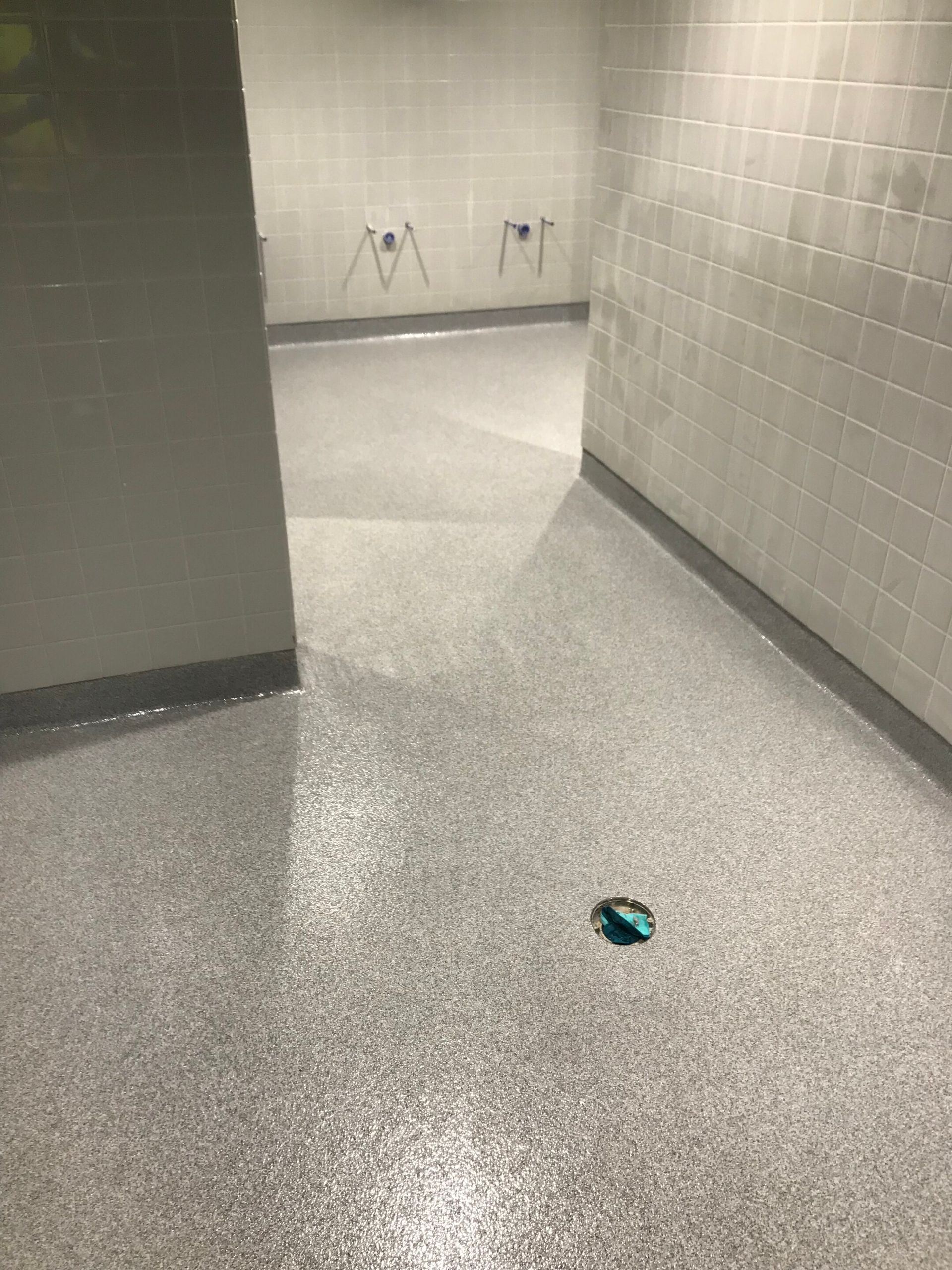 Empty tiled hallway with a small green object on the floor near the center.