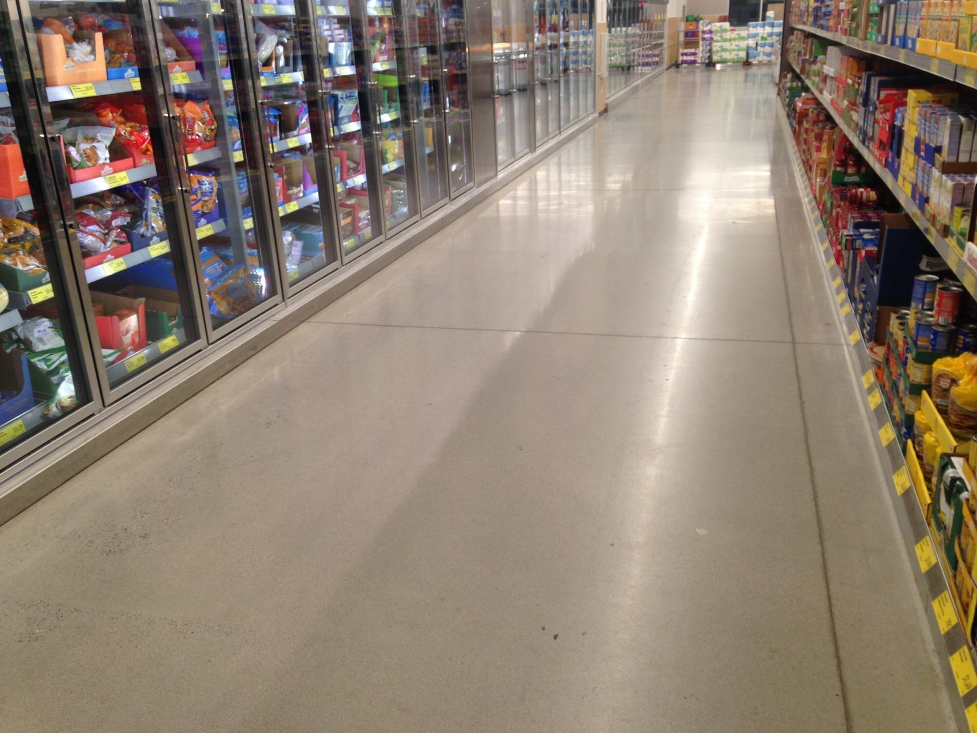 A wide store aisle with candy and snacks on shelves along both sides.