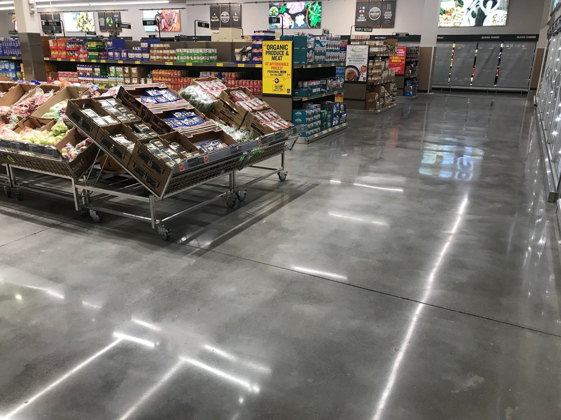 Grocery store produce aisle with stacked fruit displays and a polished concrete floor