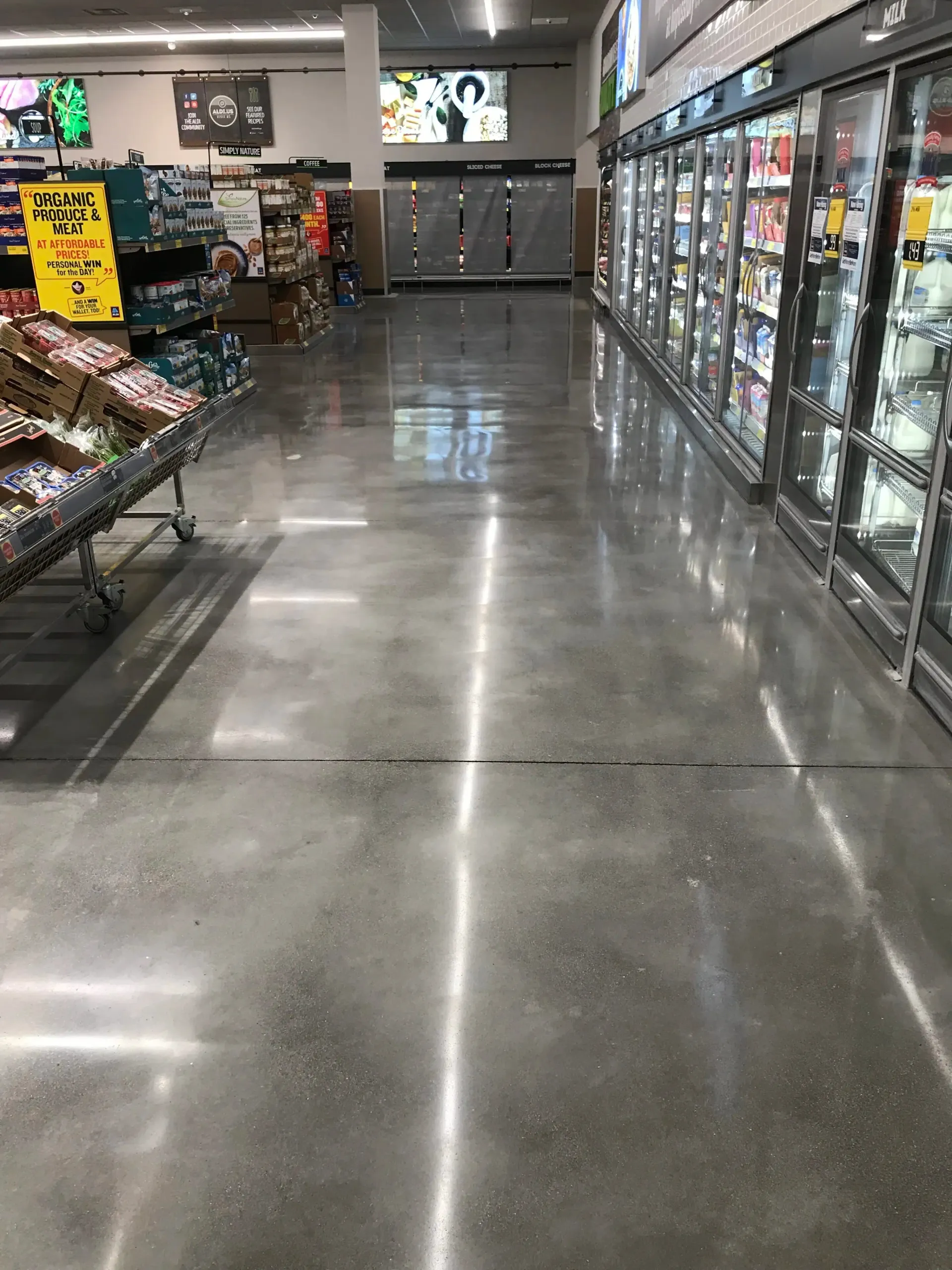 Grocery store aisle with refrigerated cases on the right and produce shelves on the left