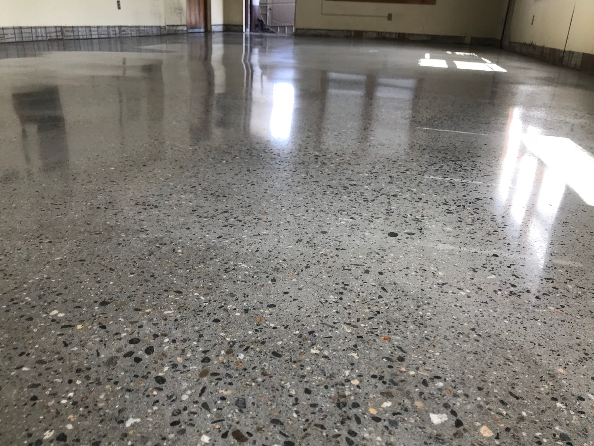 Polished speckled concrete floor reflecting light in an empty indoor space