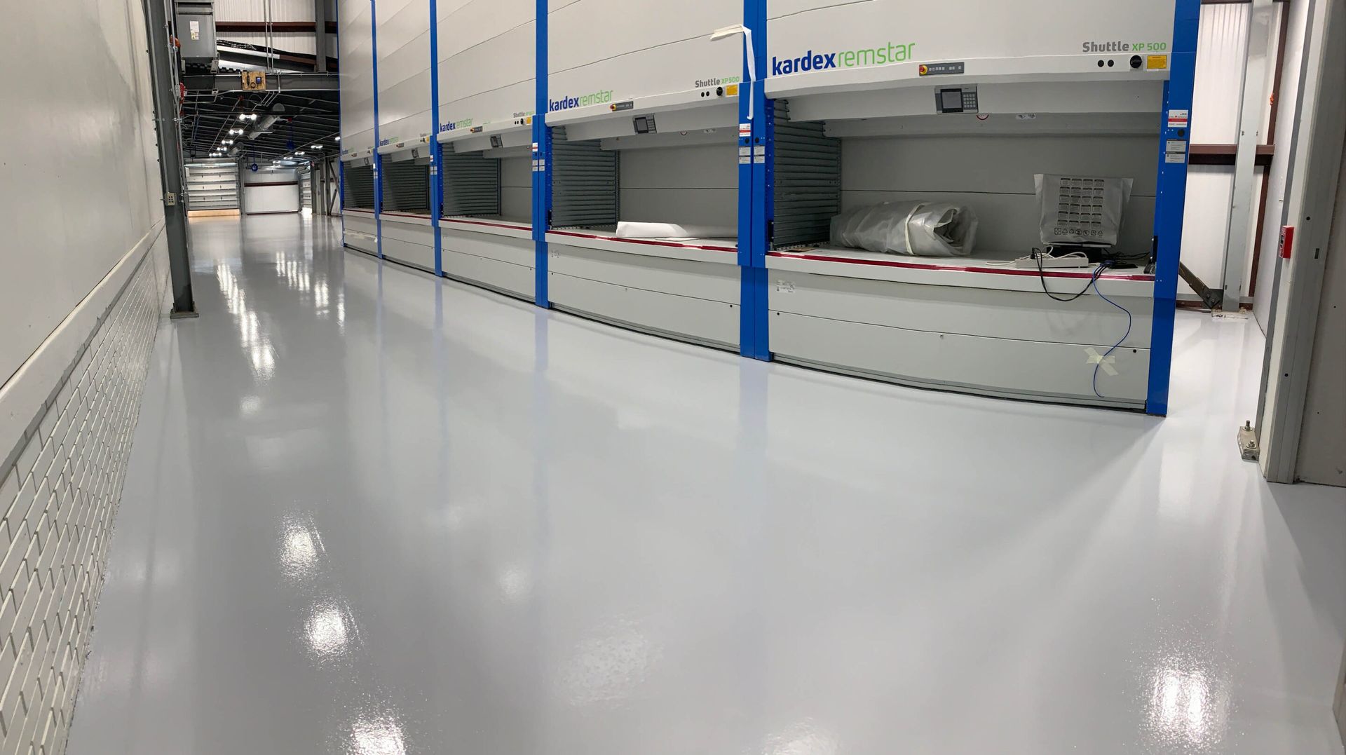 Empty polished industrial hallway with blue safety posts and machinery along the right side