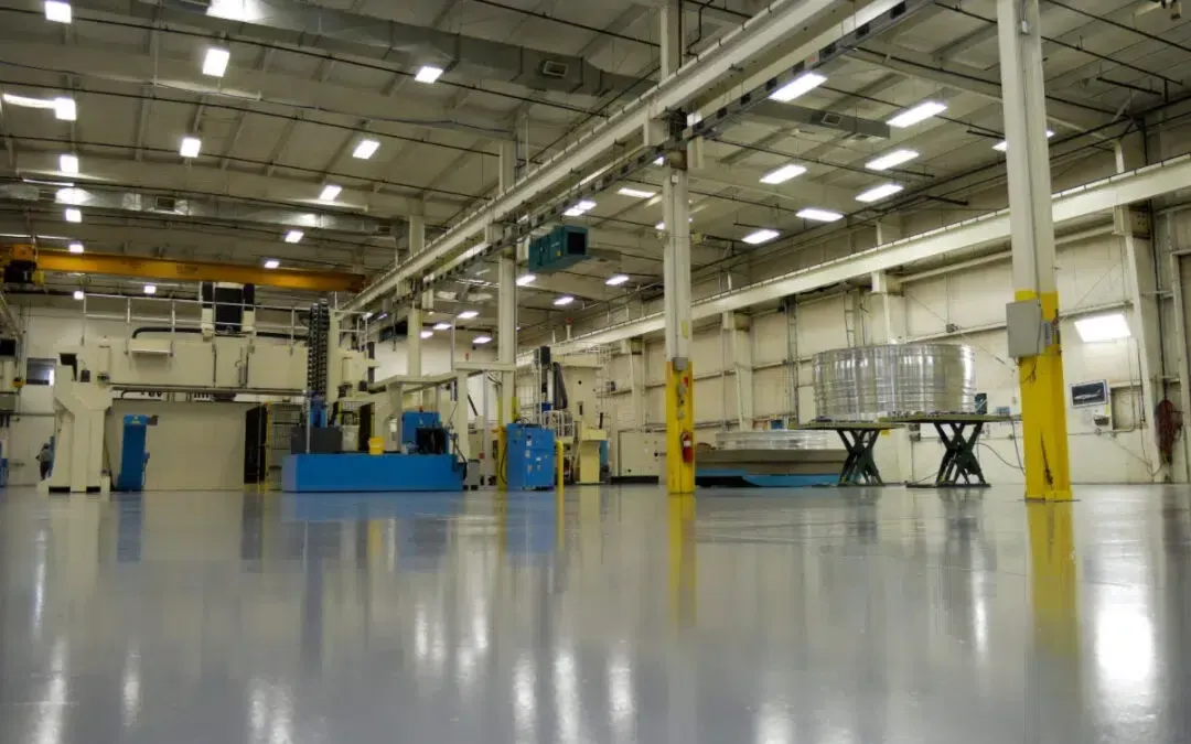 Empty industrial warehouse interior with polished floor, yellow columns, and overhead lights