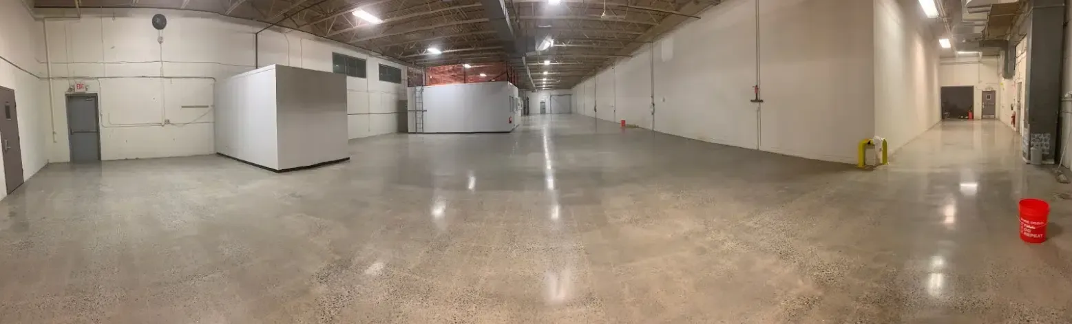 Empty warehouse interior with polished concrete floor, white walls, and overhead lights