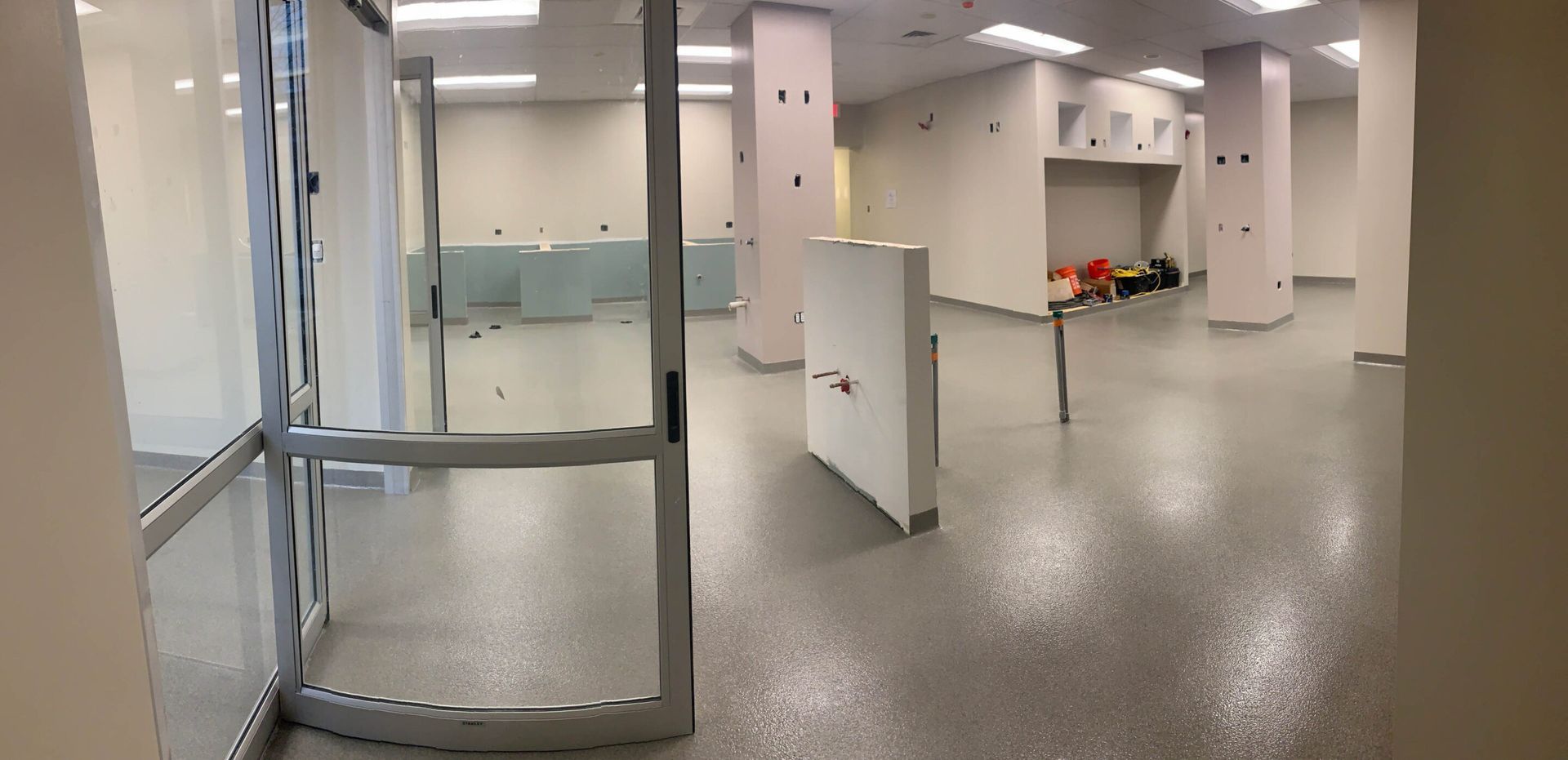 Empty modern lobby with glass doors, white columns, and a polished floor.