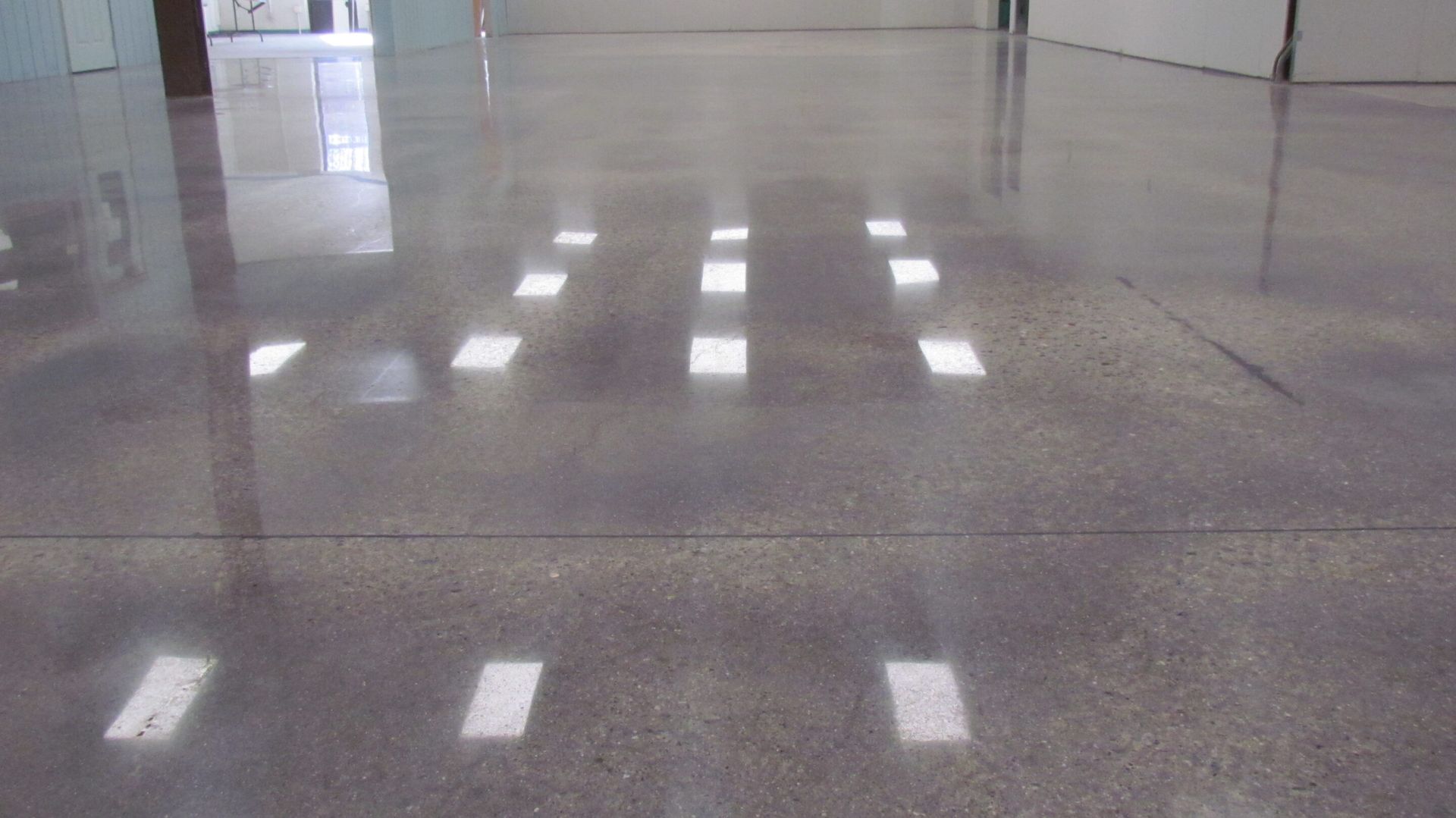 Polished gray floor with bright reflections and a doorway in the background