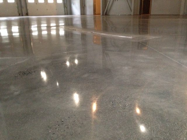 Polished gray concrete floor reflecting ceiling lights in an indoor hallway