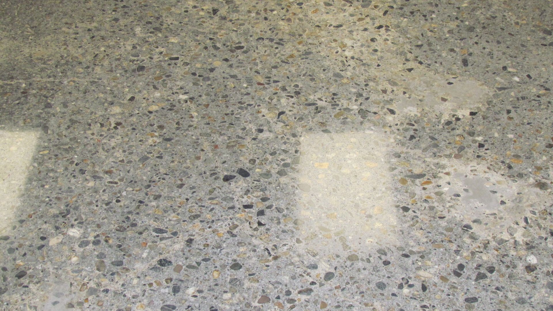 Close-up of a speckled gray terrazzo floor with bright rectangular light reflections