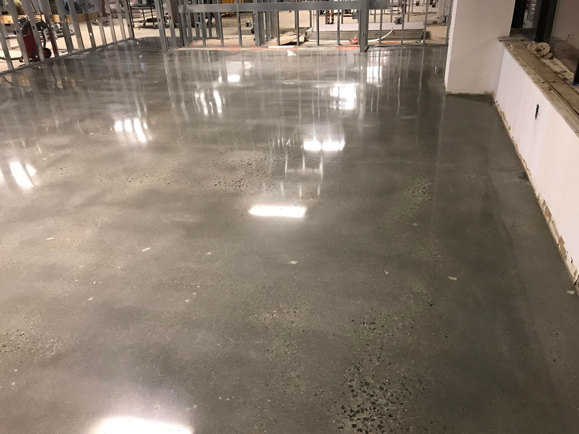 Polished concrete floor in an indoor space with bright reflections and railings in the background