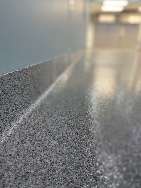 Close-up of a speckled gray countertop with a blurred hallway in the background.