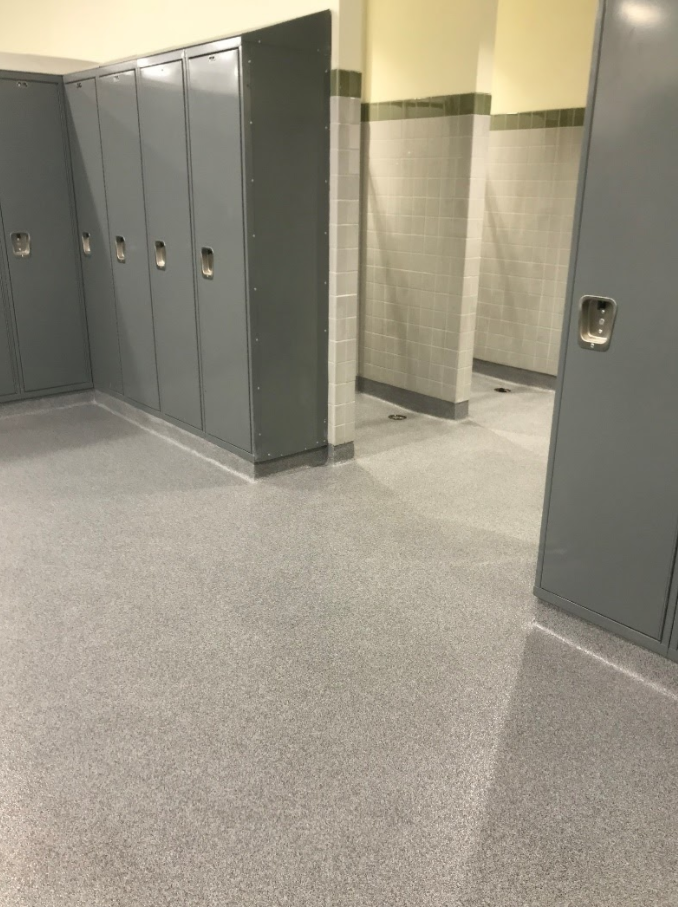 School hallway with gray lockers and a tiled restroom entrance.