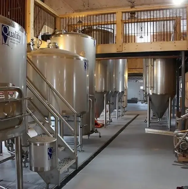 Stainless steel brewing tanks in an industrial brewery interior with walkways and pipes