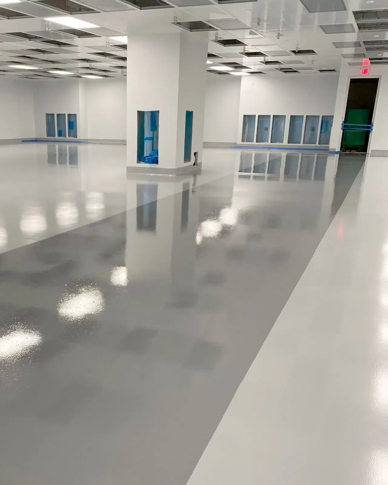 Empty modern room with glossy floor, white ceiling tiles, and blue wall panels.