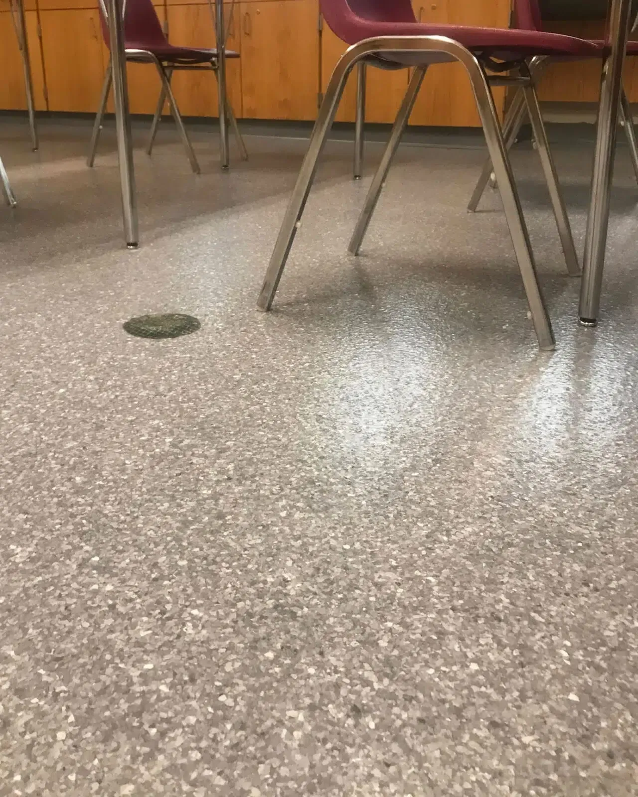 Classroom floor with a small spill near chair legs and tables.
