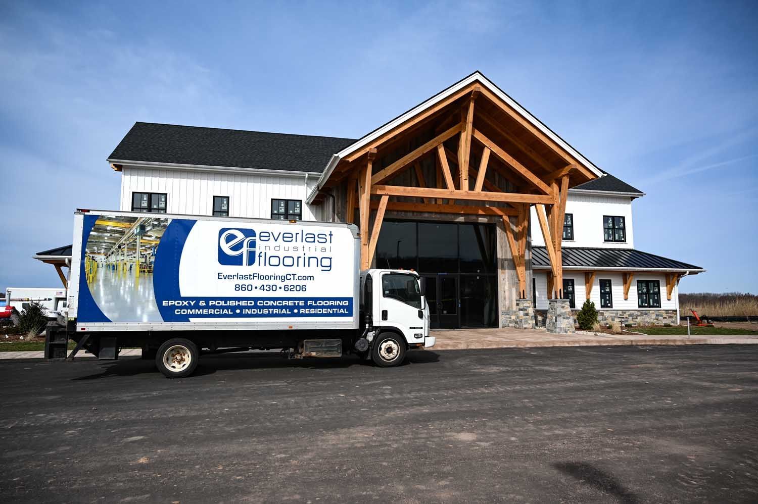Construction truck outside a white building with a large wooden entrance canopy.