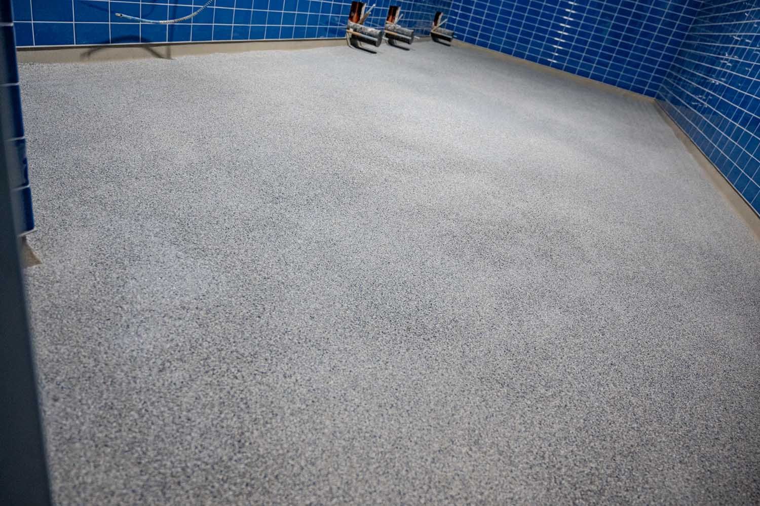 Empty tiled indoor room with blue walls and two small valves near the back wall