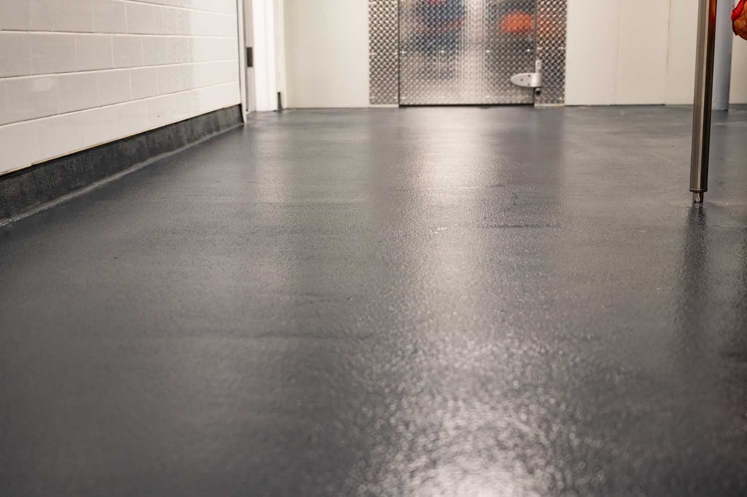 Empty hallway with glossy dark floor, white walls, and closed doors at the end
