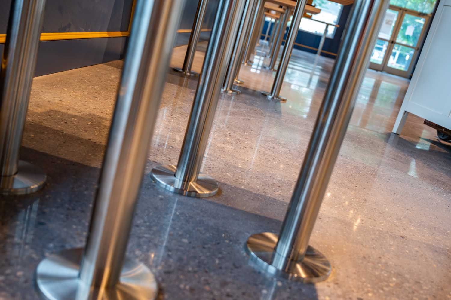 Metal queue barriers on a polished lobby floor near glass doors.