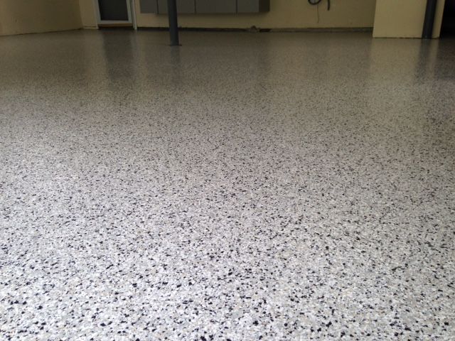 Empty speckled floor in an indoor room with a blurred wall in the background