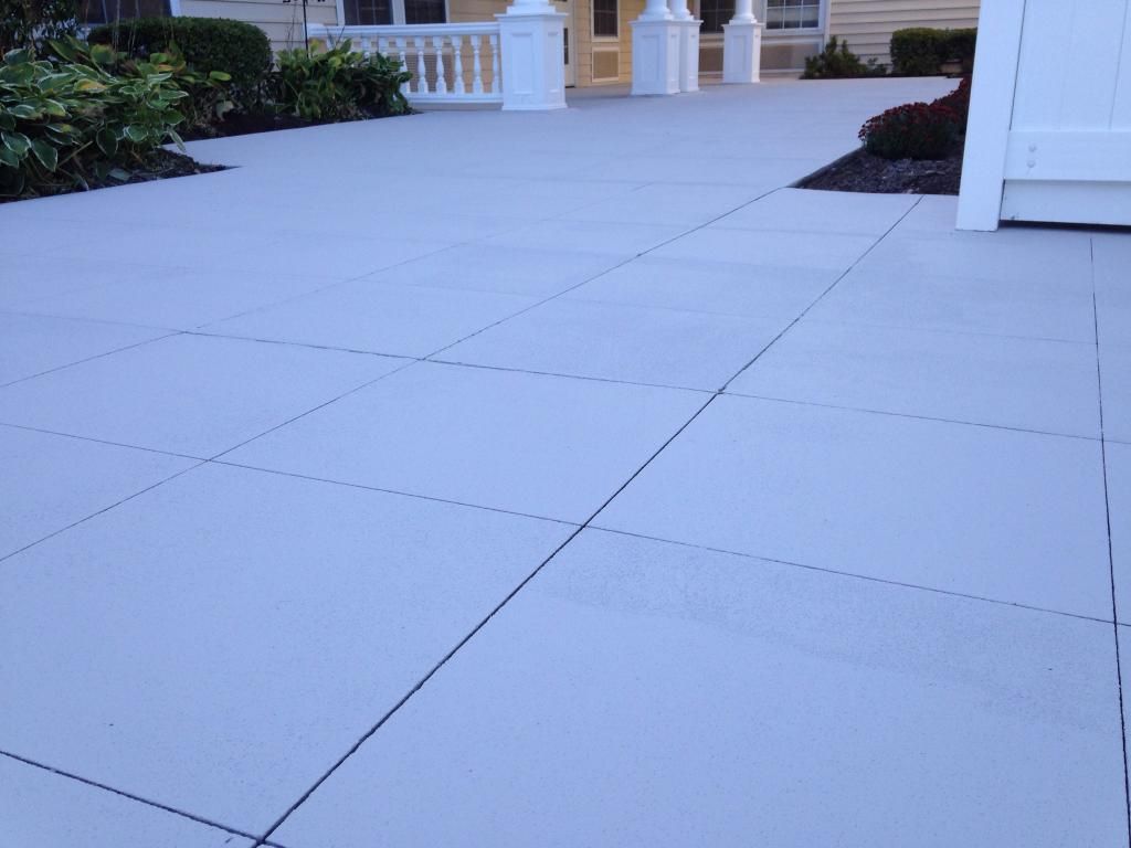 Empty light-gray tiled walkway leading to a building entrance with white columns and yellow doors