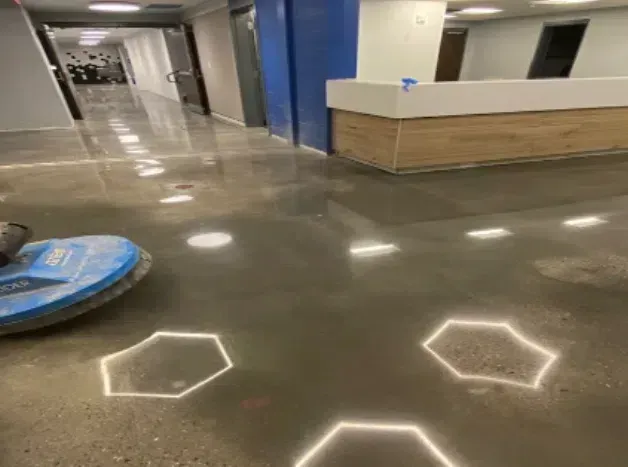 Indoor hallway with glossy floor, hexagonal light reflections, and a blue cleaning robot on the left.