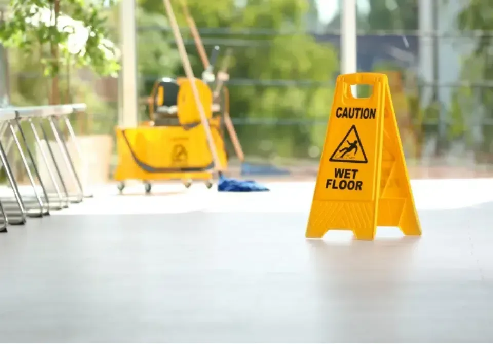 Yellow caution sign warning of a wet floor in a bright indoor hallway