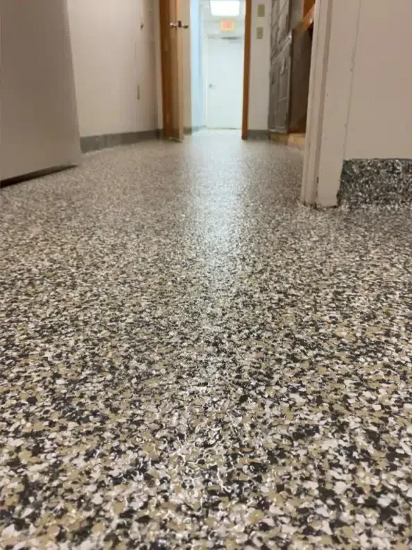 Speckled terrazzo floor in a hallway leading to an open doorway
