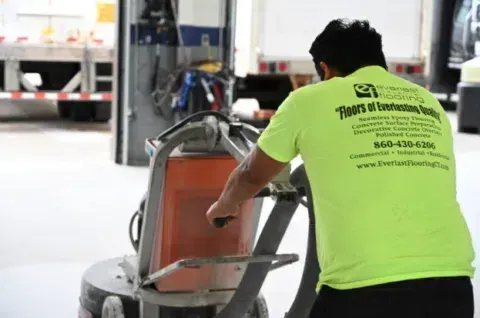 Worker in neon green shirt loading a cart in an industrial garage setting