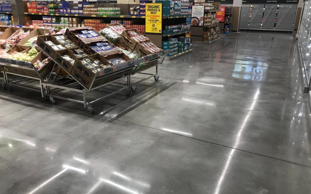 Empty supermarket aisle with shiny floor, produce displays, and shelving in the background