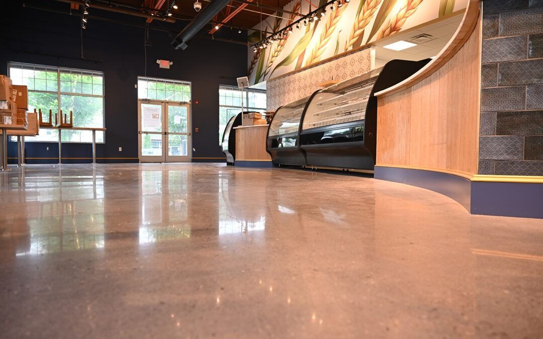 Empty modern lobby with polished floor, benches along the wall, and glass doors at the far end