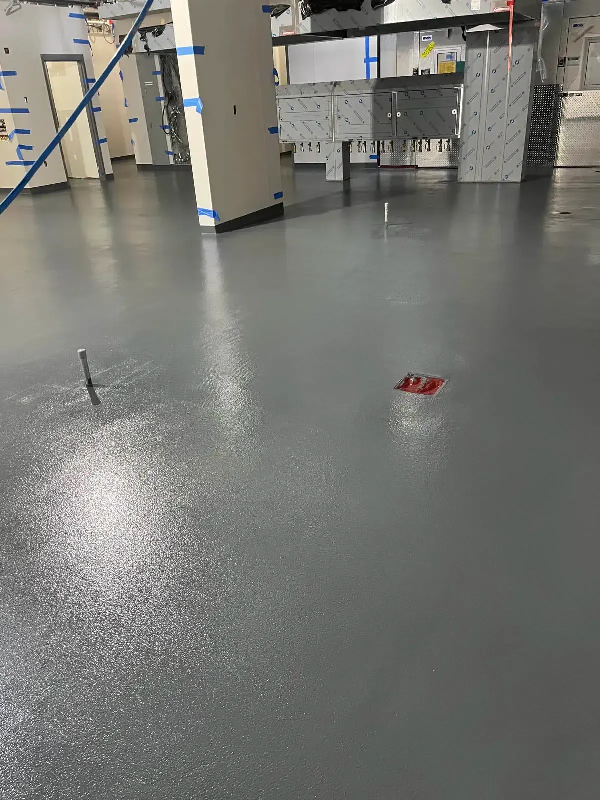 Empty indoor gym floor with a small red object near the center and lockers in the background