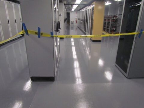 Yellow caution tape blocking a glossy hallway between gray server racks in a data center