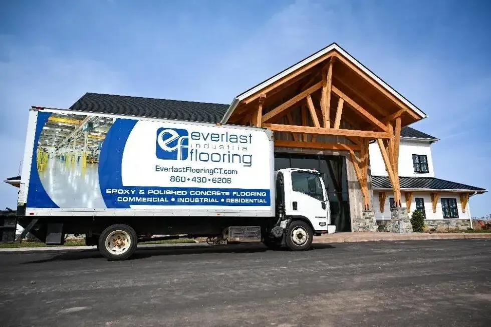 Everlast Flooring delivery truck parked outside a large building with a wooden entrance arch