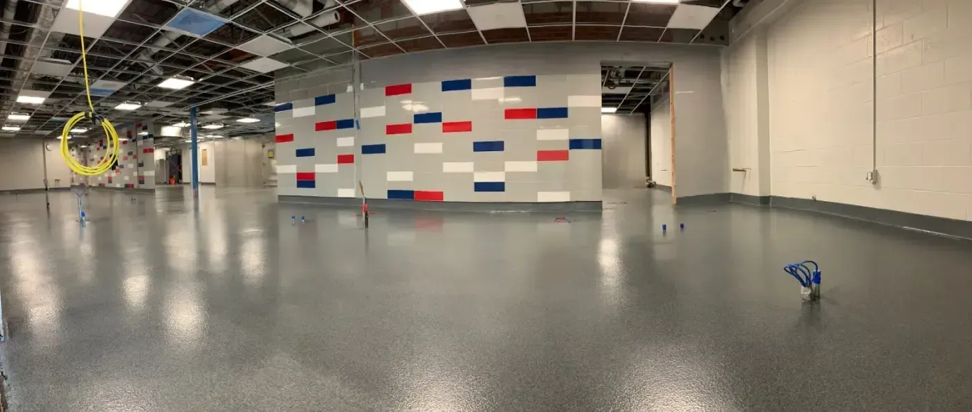 Empty warehouse-like room with polished floor, white walls, and a red-blue pattern on the far wall