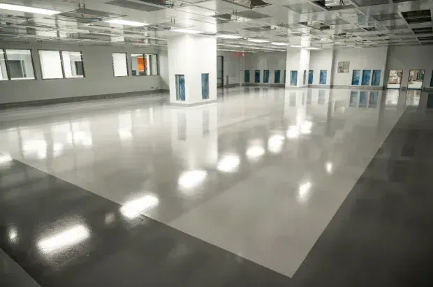 Empty glossy indoor hall with white walls, windows, and reflections on the polished floor