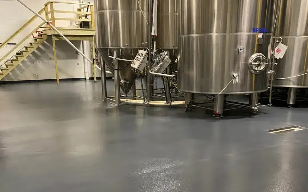 Large stainless steel tanks in a clean, industrial setting with polished gray floors