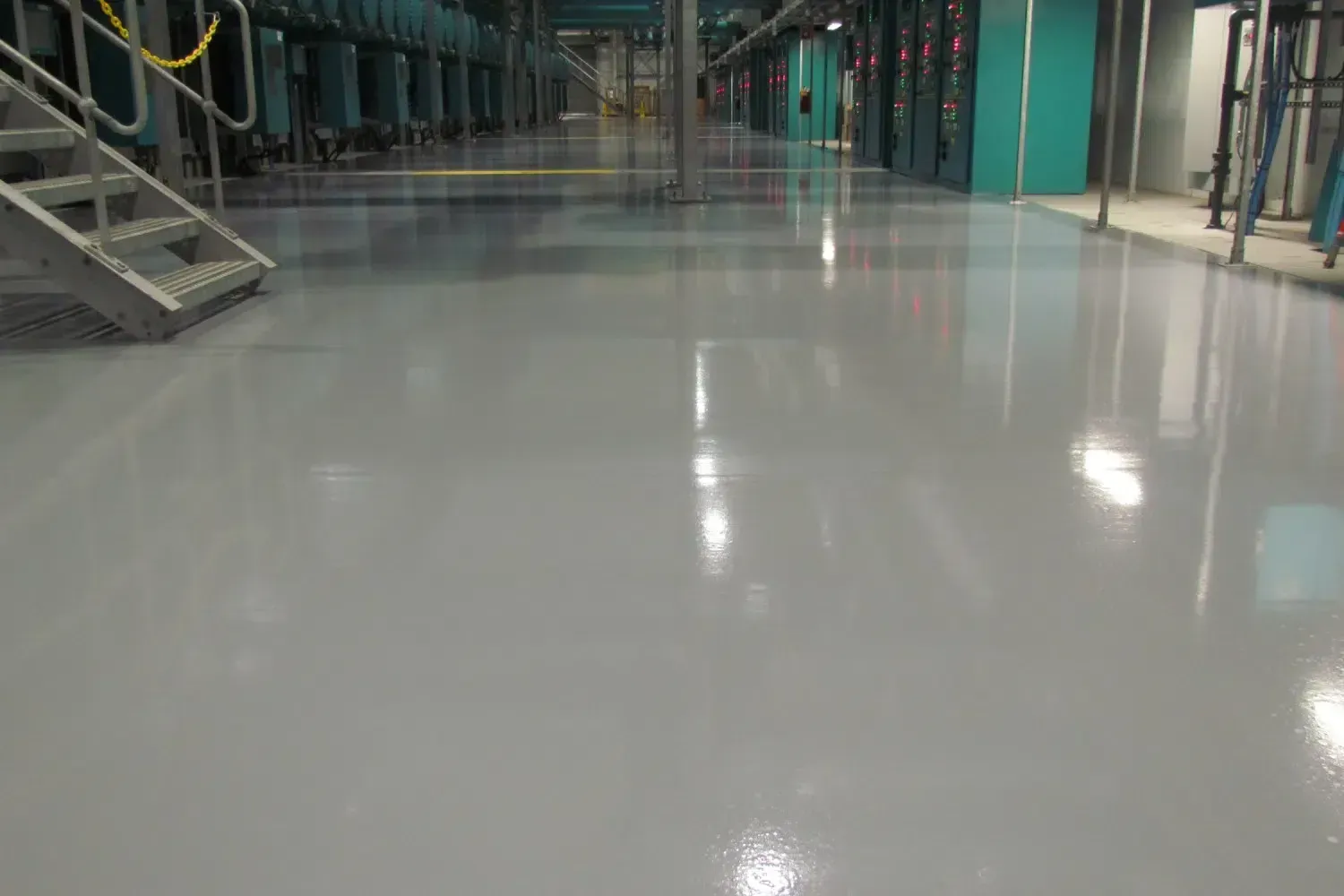 Worker smoothing wet concrete floor with a trowel in a tiled hallway