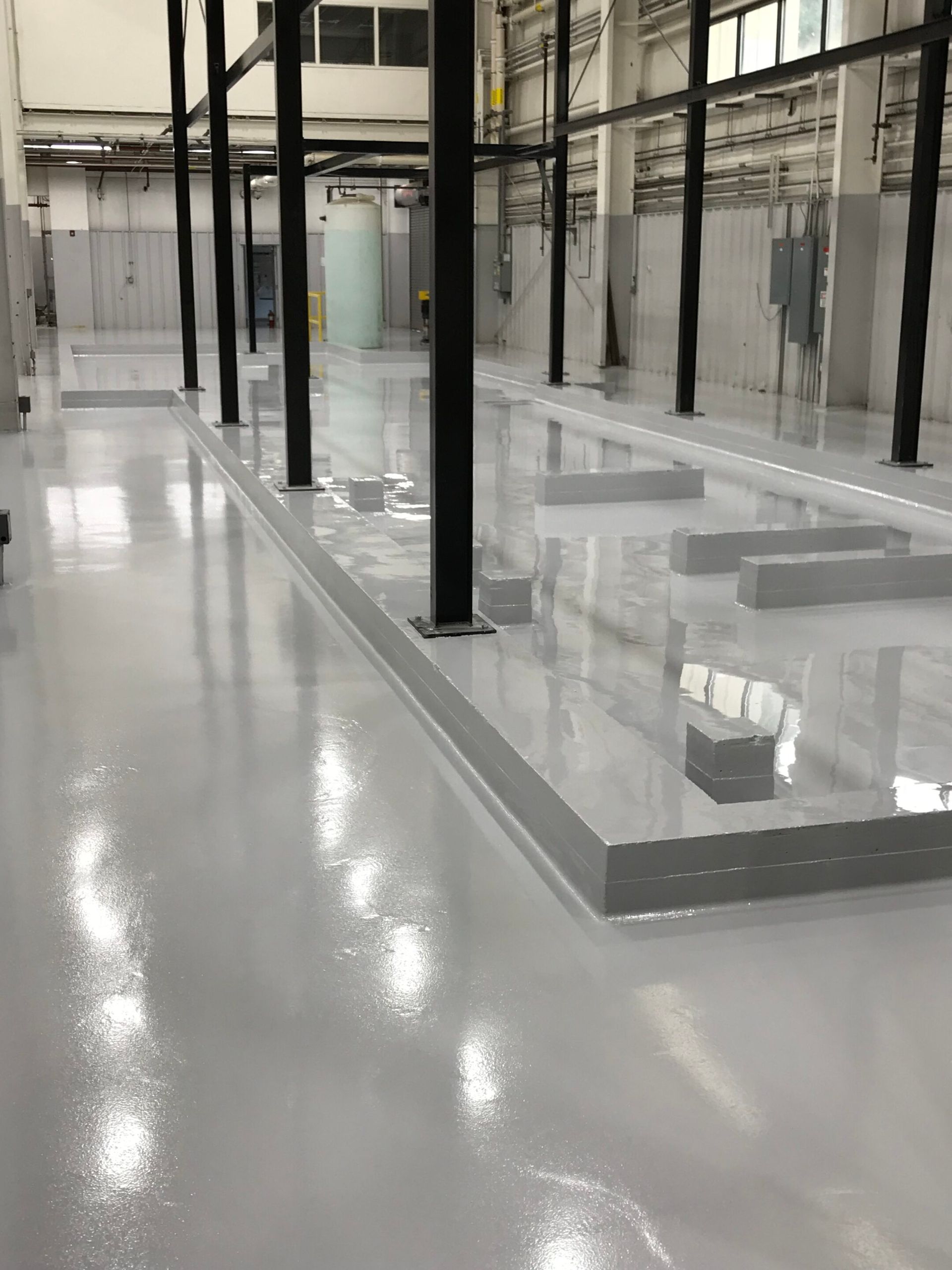 Empty industrial interior with glossy gray floor and black support columns